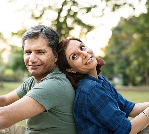 man and woman sitting outside with their backs together